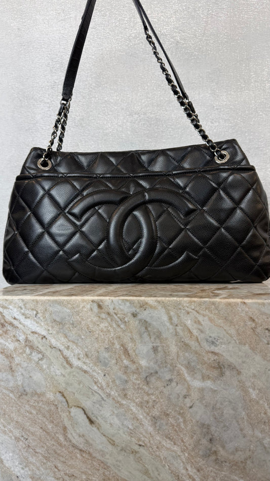 Black quilted handbag with Chanel logo on a marble surface
